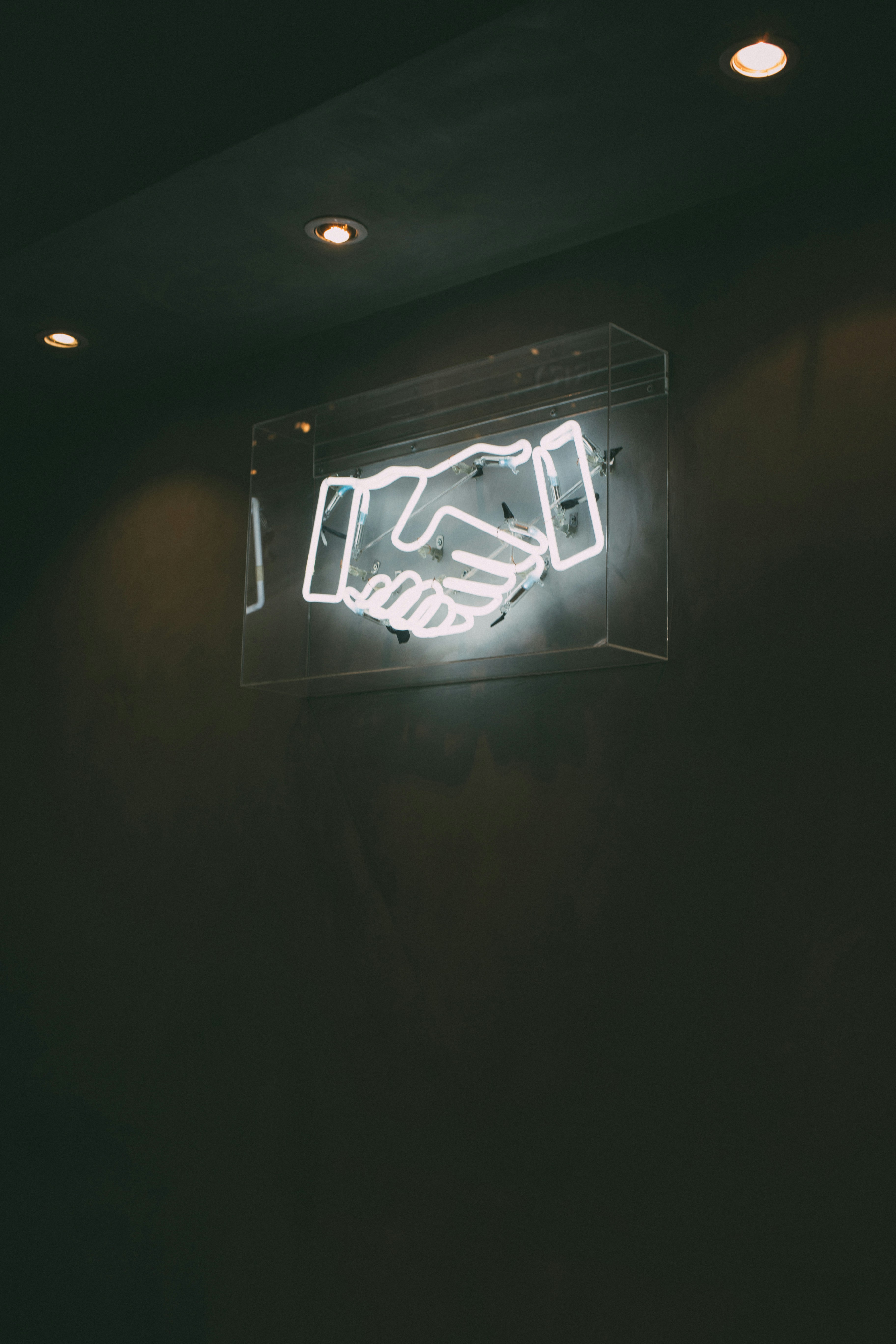 A neon sign depicting a handshake in a dark room