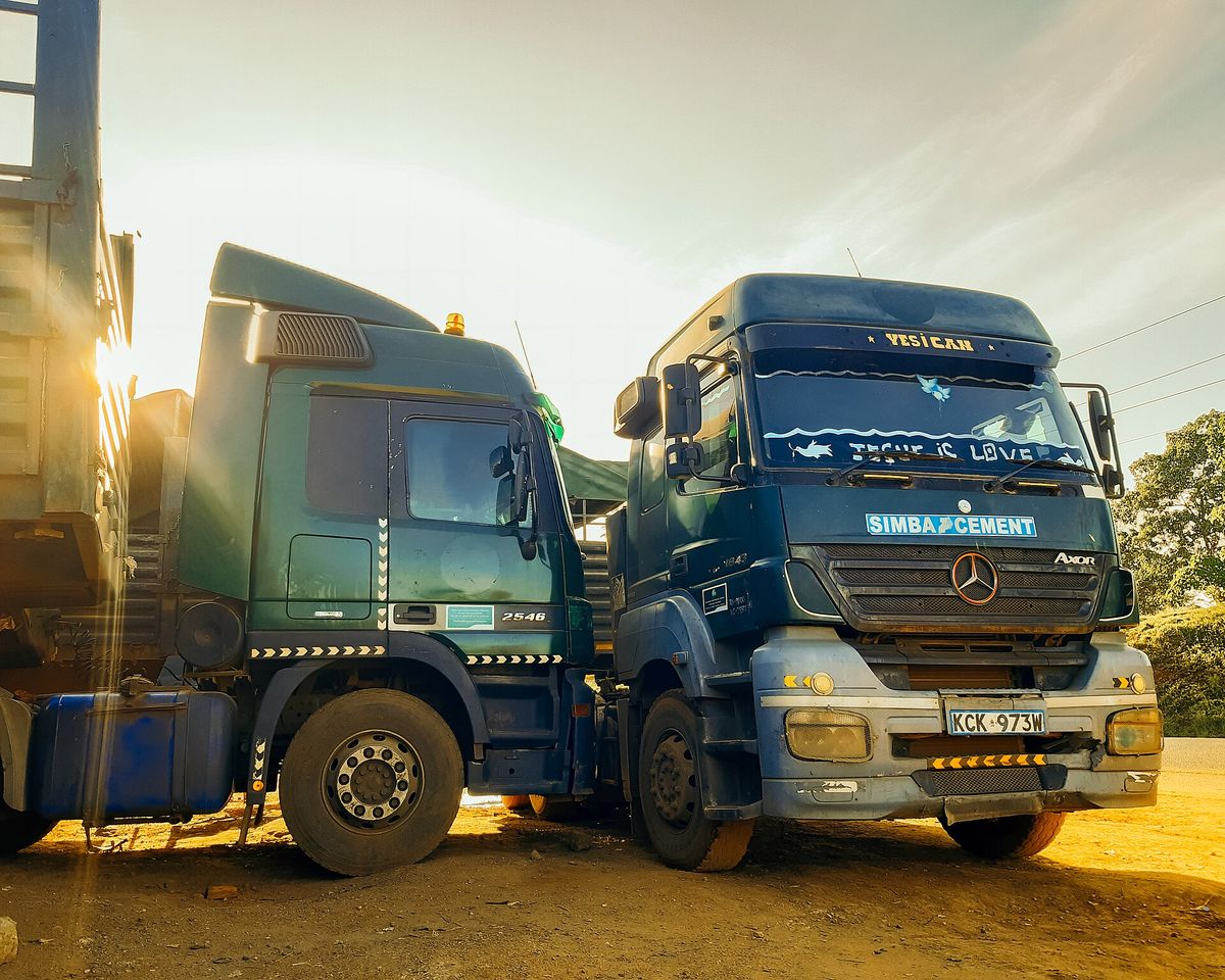 Two long-haul trucks parked side by side at sunset in Kenya
